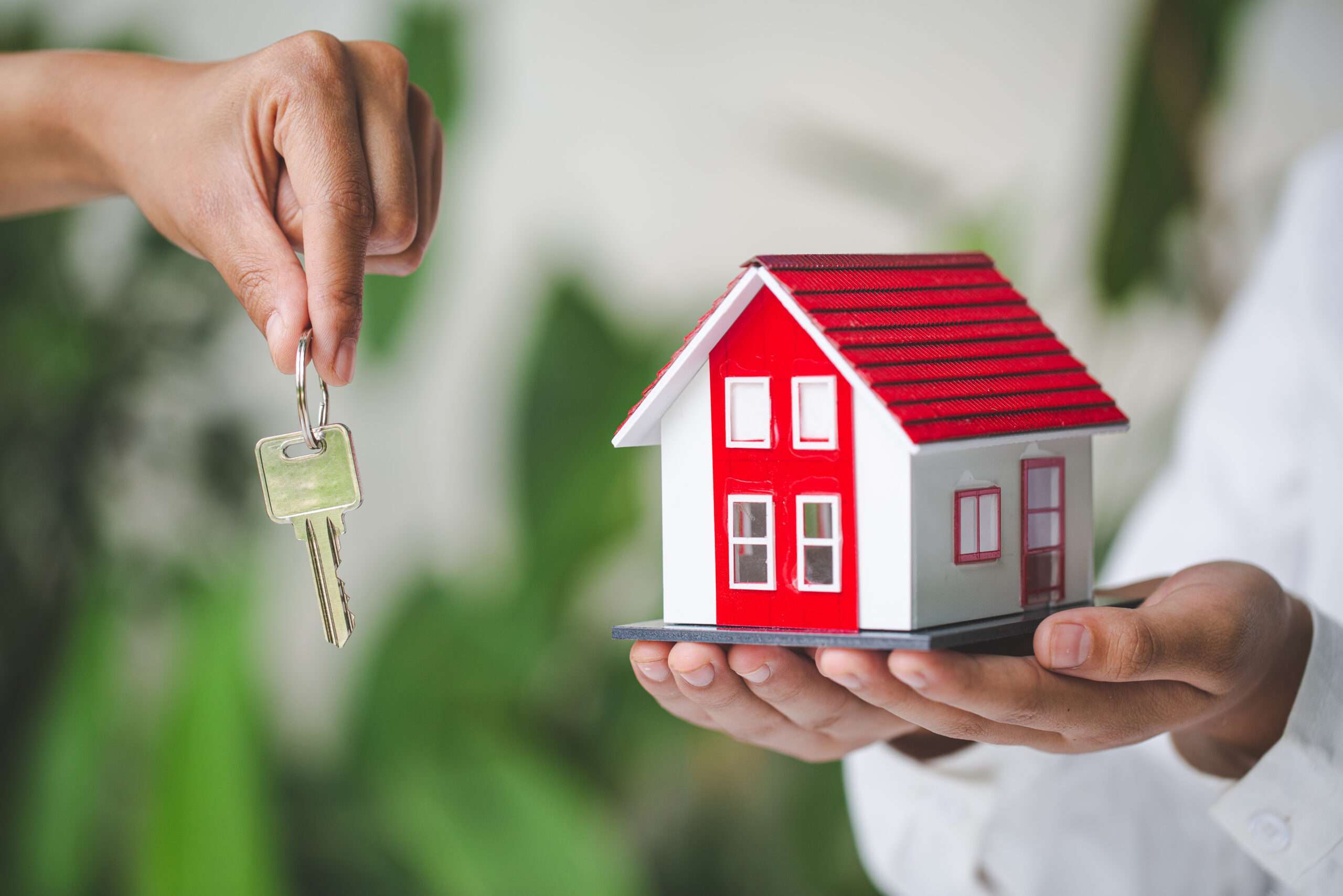 Your new house, real estate agent holding house key to his client after signing contract agreement in office,concept for real estate, renting property